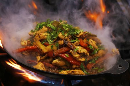 Photo for Mexican food, chicken fajitas served on a hot smoking sizzling plate - Royalty Free Image
