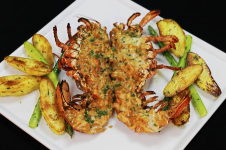 lobster thermidor served with glazed potato and asparagus in a platter, black background