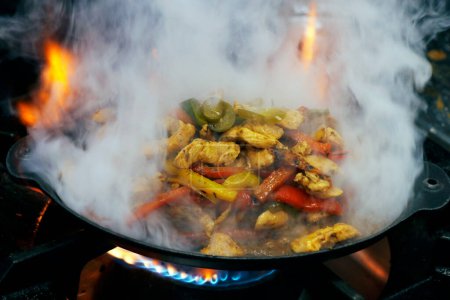 Photo for Mexican food,fajitas with chicken, beef and peppers served on a hot smoking sizzling plate - Royalty Free Image