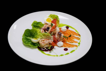 Photo for Prawns cocktail and marinated salmon gravlax salad with baby gem lettuce and herbs in a white plate with black background - Royalty Free Image