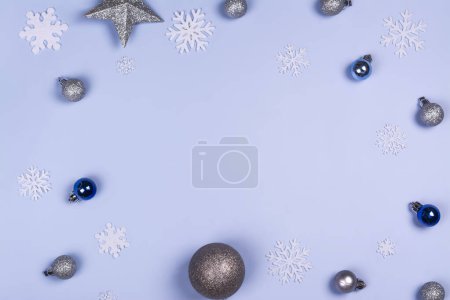 Photo for Christmas background with white snowflakes and holiday silver decorations on blue. Copy space. Top view - Royalty Free Image