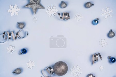 Téléchargez les photos : Fond de Noël avec des flocons de neige blancs et des décorations argentées de vacances sur bleu. Espace de copie. Vue du dessus - en image libre de droit