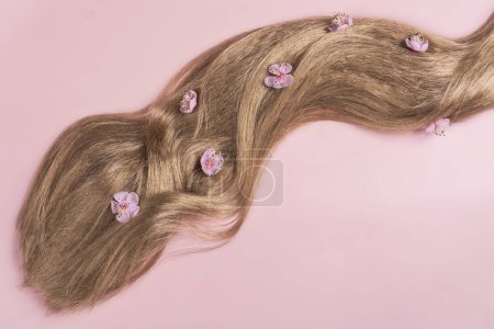Photo for Long blond hair with sakura flowers in it. International Hair Day. Bad Hair Day. Copy space - Royalty Free Image