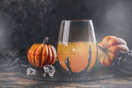 Photo for Halloween orange cocktail in spooky skeletons hand glasses - Royalty Free Image