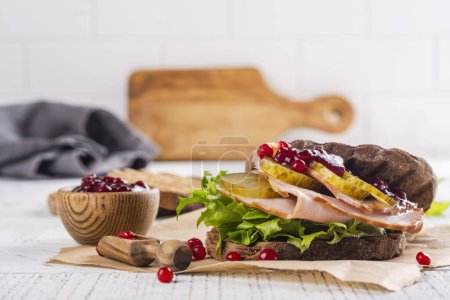 Photo for Homemade leftover thanksgiving day sandwich with turkey, cranberry sauce and vegetables. White wooden background - Royalty Free Image