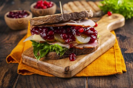 Foto de Sandwich casero de día de acción de gracias con pavo, salsa de arándanos y verduras. Estilo rústico oscuro - Imagen libre de derechos