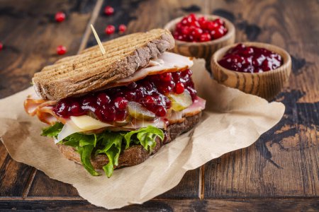 Photo for Homemade leftover thanksgiving day sandwich with turkey, cranberry sauce and vegetables. Dark rustic style - Royalty Free Image