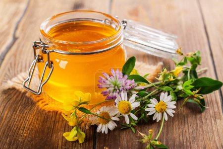 Foto de Tarro de vidrio con miel líquida floral, flores y tarro de miel. Copiar espacio - Imagen libre de derechos