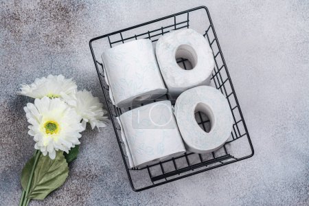 Téléchargez les photos : Panier avec rouleaux de papier toilette et fleur blanche sur fond de pierre. Journée internationale du papier toilette. Vue du dessus - en image libre de droit