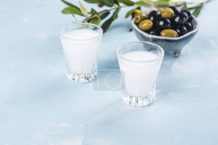 Foto de Vodka ouzo griego tradicional y aceitunas marinadas sobre fondo de pizarra azul. Copiar espacio - Imagen libre de derechos