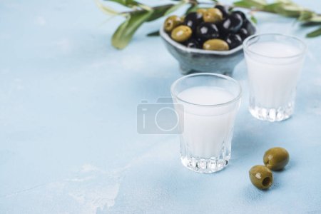 Photo for Traditional greek vodka ouzo and marinated olives on blue slate background. Copy space - Royalty Free Image
