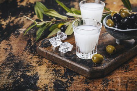 Photo for Traditional greek vodka ouzo and marinated olives on rustic wooden table - Royalty Free Image