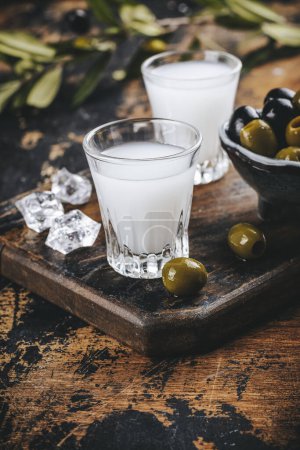 Téléchargez les photos : Vodka traditionnelle grecque ouzo et olives marinées sur table rustique en bois - en image libre de droit