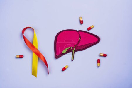 Photo for Liver, yellow and red ribbon, pills. World hepatitis day. National liver health awareness month. Liver transplantation, donation background. Save patient life in hospital with liver transplant - Royalty Free Image