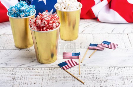 Foto de Copas de papel dorado con palomitas rojas, azules y blancas. Colores estadounidenses para el 4 de julio. Snack food para la celebración del día de la independencia de EE.UU. - Imagen libre de derechos
