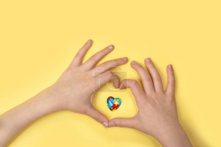 Photo for Autistic pride day - 18 june. World autism awareness day or month background. Child hands and jigsaw heart symbol on yellow background. Copy space - Royalty Free Image