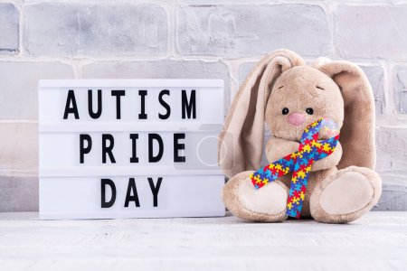 Téléchargez les photos : Jour de la fierté autiste - 18 juin. Journée mondiale de sensibilisation à l'autisme ou fond mois. Jouet lapin mignon avec ruban de scie sauteuse dans les pattes Espace de copie - en image libre de droit