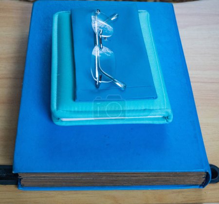 Lunes Azul. Un libro, un cuaderno y un estuche con gafas, todo en tonos azules. El día más deprimente del año. El día del suicidio y la depresión. Foto de alta calidad