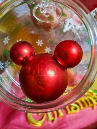 New Years Eve Mickey Mouse Toy in a Glass Ball Close Up. New Years toys hung on a rope on a white background. High quality photo