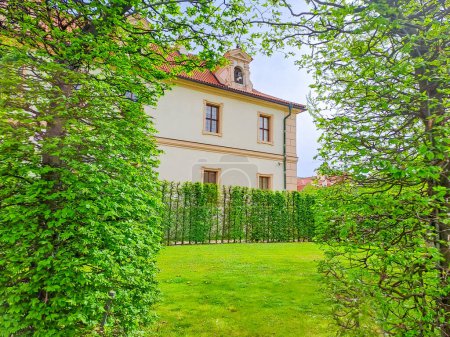 Arco verde vivo de arbustos en los jardines Wallenstein con palacio barroco en la ciudad menor de Praga. Este palacio es actualmente el hogar del Senado checo. Foto de alta calidad
