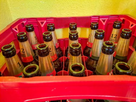 Téléchargez les photos : Bouteille de bière vide dans des caisses en plastique rouge au soleil, bouteilles de bière en verre prêtes à être recyclées. Photo de haute qualité - en image libre de droit