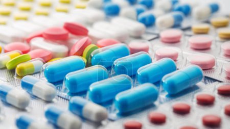 Téléchargez les photos : Pile de pilules médicales en rouge, bleu et jaune dans un emballage en plastique argenté - en image libre de droit