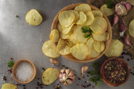 Pile of crispy potato chips lying on an old concrete table in kitchen. Concept of fast food background. Free place for text, top view.
