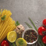 Italian food background on stone table. Macaroni, basil and vegetables.