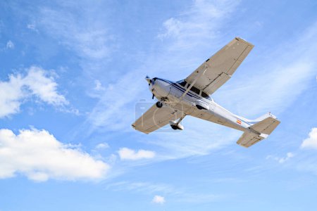 Samolot ultralekki lecący na niebieskim niebie z białymi chmurami