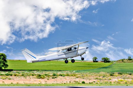Photo for Single engine ultralight airplane taking off from airfield under blue sky with white clouds - Royalty Free Image