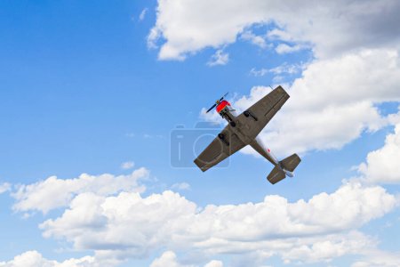 Photo for View of an aerobatic plane (aerodyne), in flight under a blue sky with white clouds. flight exhibitions - Royalty Free Image