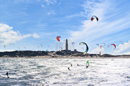 Photo for People practicing kitesurfing on the beach of Los Caos de Meca, next to the Trafalgar Lighthouse, Barbate, Cdiz - Royalty Free Image
