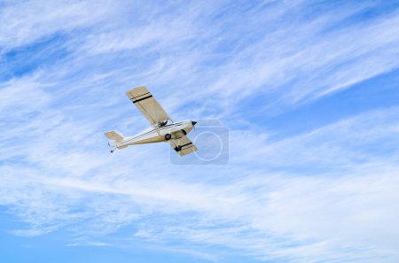 Einmotoriges Ultraleichtflugzeug fliegt mit weißen Wolken in den blauen Himmel