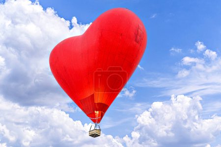 Photo for Red heart-shaped hot air balloon flying over a blue sky with white clouds - Royalty Free Image