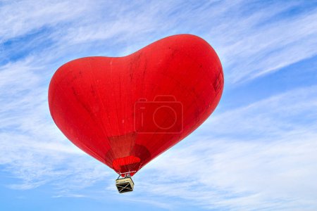 Téléchargez les photos : Montgolfière rouge en forme de cœur survolant un ciel bleu avec des nuages blancs - en image libre de droit