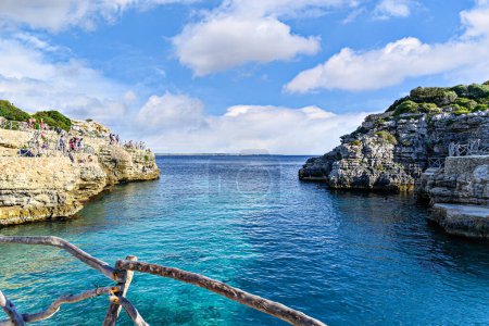 Téléchargez les photos : Cala En Brut, Minorque, Îles Baléares, Espagne ; 14 mai 2023 : Vues de la crique populaire où les gens sautent des rochers dans la mer en été. - en image libre de droit