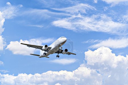 Passenger plane landing at the airport, under a blue sky with white clouds