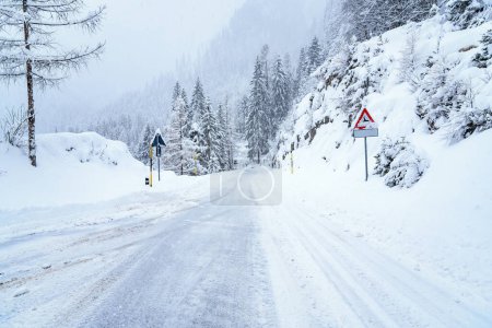 Snowy road in the European Alps during heavy snowfall in winter