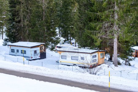 Téléchargez les photos : Caravanes et campeurs dans un camping enneigé en montagne en hiver - en image libre de droit