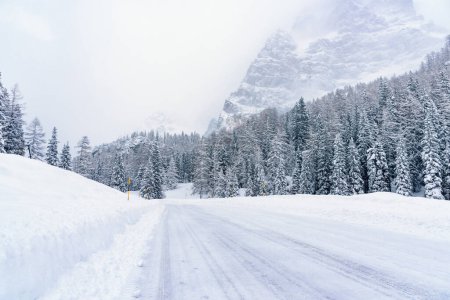 Foto de Camino nevado del paso de la montaña en los Alpes durante una ventisca en invierno. Condiciones de conducción peligrosas. - Imagen libre de derechos