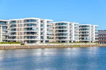 Téléchargez les photos : New apartment buildings along a river harbour on a clear summer day. Bremerhaven, Germany. - en image libre de droit
