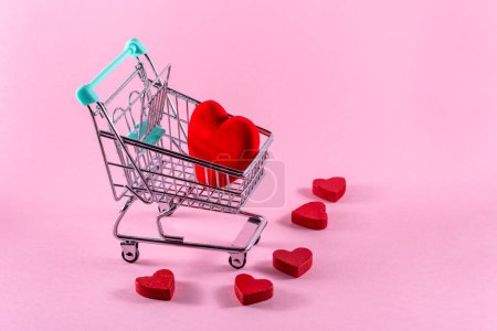 Téléchargez les photos : Red heart on a shopping trolley against pink background. Valentines day shopping concept. Copy space. - en image libre de droit