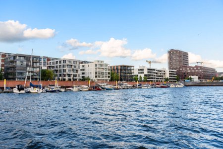 Foto de Modern waterfront apartment buildings along a river harbour on a clear summer day. Bremen, Germany. - Imagen libre de derechos