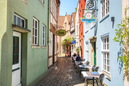 Foto de Bremen, Alemania - 21 de junio de 2022: Almuerzo al aire libre en una estrecha calle adoquinada en el distrito histórico de Schnoor - Imagen libre de derechos