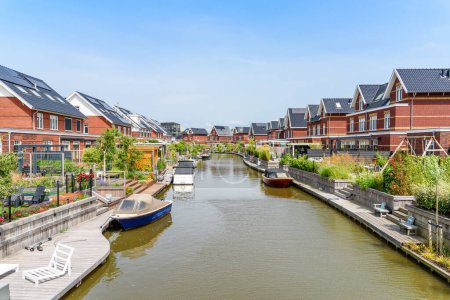 Téléchargez les photos : Maisons modernes en briques écoénergétiques avec panneaux solaires sur le toit le long d'un canal aux Pays-Bas par une journée d'été claire - en image libre de droit