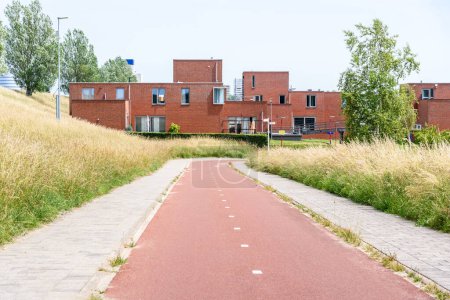 Foto de Sendero para bicicletas abandonado en una urbanización en un día soleado de verano. Casa de ladrillo moderno están en el fondo. Zoetermeer, Países Bajos. - Imagen libre de derechos