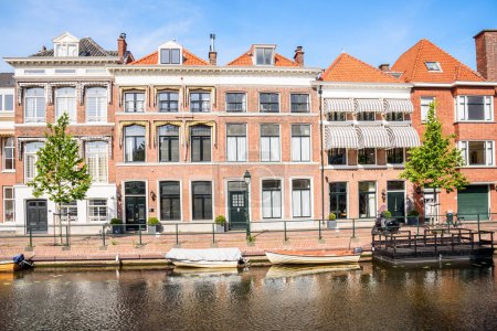 Foto de Casas de ladrillo rojo renovadas a lo largo de un canal en un día claro de verano. La Haya, Países Bajos. - Imagen libre de derechos