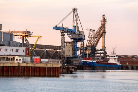 Foto de Buque de carga amarrado a un muelle comercial en un puerto fluvial al atardecer. Bremen, Alemania. - Imagen libre de derechos