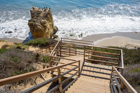 An einem sonnigen Herbsttag führt eine verlassene Treppe hinunter zu einem einsamen Sandstrand an der Küste Kaliforniens. Malibu, CA, USA.