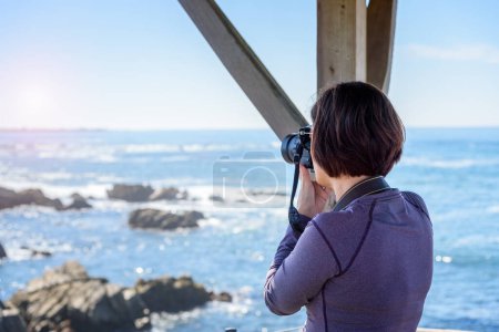 Foto de Turista mujer tomando fotos del océano en un día soleado de otoño. Monterey, CA, Estados Unidos. - Imagen libre de derechos